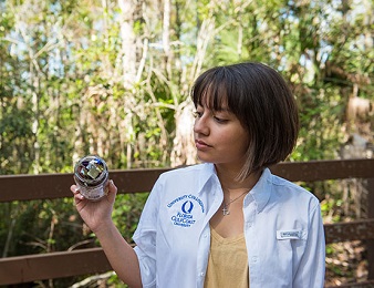 Fabiana Solano shows a jarful of glitter pulled from under the Merwin Hall boardwalk. Photos: James Greco/FGCU