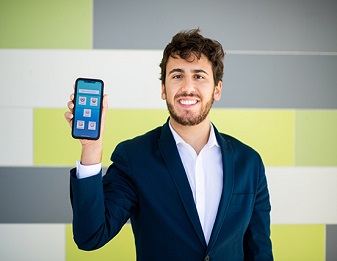 Jack Hellmer holding phone displaying screen of the app he is building
